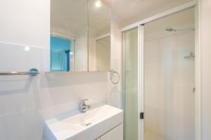 een witte badkamer met een wastafel en een douche bij Munna Beach Apartments in Noosaville