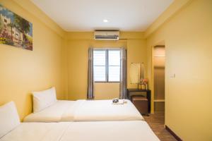 ein Hotelzimmer mit zwei Betten und einem Fenster in der Unterkunft The Corner Ratchada in Bangkok