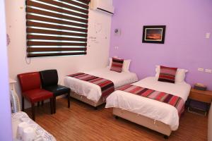 a room with two beds and a red chair at 500Km Home in Hualien City