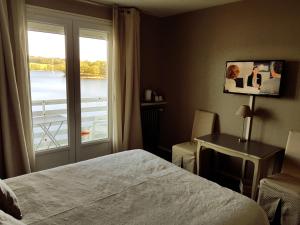 1 dormitorio con cama y ventana con vistas en Hotel Restaurant La Caravelle, en Peyrat-le-Château