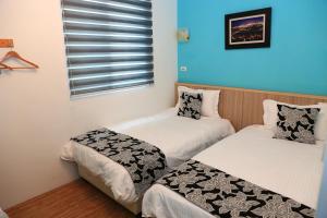 two twin beds in a room with a window at 500Km Home in Hualien City