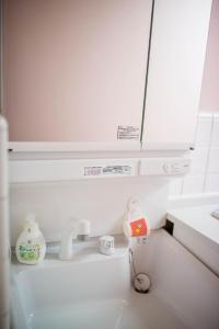 a white kitchen with a sink and a mirror at Kumano House in Kyoto