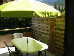 a table with a yellow umbrella on a patio at Appartement dans maison Entre Savines et Embrun in Crots