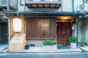 a house with a gate and two potted plants on a street at Kumano House in Kyoto