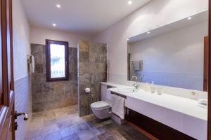 a bathroom with a sink and a toilet and a mirror at Mansion Ses Oliveres in S'Horta +20 photos