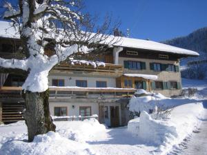 ein schneebedecktes Gebäude mit einem Baum davor in der Unterkunft Ferienhof Kösel in Missen-Wilhams