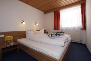 a bedroom with a large white bed with a window at Appartementhaus Salzgeber in Nauders