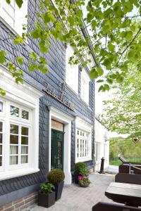 - un bâtiment bleu et blanc avec une porte verte dans l'établissement Zu den Drei Linden, à Wermelskirchen