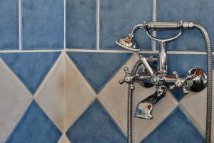 a shower faucet in a bathroom with blue tiles at LIVAS Apartment in Ierápetra +9 photos