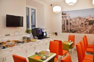 ein Esszimmer mit orangefarbenen Stühlen und einem Flachbild-TV in der Unterkunft Navona Luxury Guesthouse in Rom