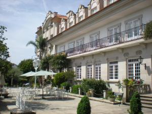 budynek ze stołami i krzesłami przed nim w obiekcie Hotel - Restaurante Casa Rosita w mieście Cambados