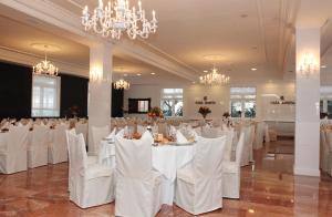 Pokój z białymi stołami, krzesłami i żyrandolami w obiekcie Hotel - Restaurante Casa Rosita w mieście Cambados