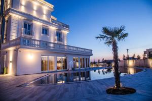 a building with a palm tree next to a swimming pool at Hotel Villa Pascucci in Durrës