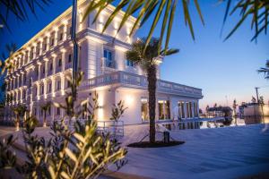 a white building with a palm tree in front of it at Hotel Villa Pascucci in Durrës