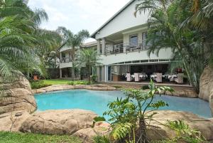 a house with a swimming pool in front of a house at uShaka Manor Guest House in Durban