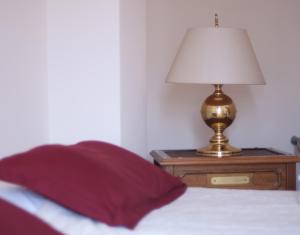 a bed with a red pillow and a lamp on a night stand at Château de Lastours in Valence-dʼAgen