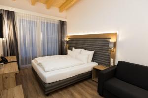 1 dormitorio con cama blanca y sofá en The Ischgl Lodge en Ischgl