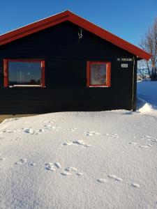 Fjellbu Two-bedroom Cottage في جيلو: مبنى أسود مع آثار أقدام في الثلج