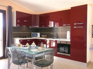 uma cozinha com armários vermelhos e uma mesa com cadeiras em Casa Maria Teresa em Cardedu