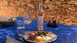 a table with a plate of food and a bottle of wine at Ryad de Vignes " Le Val d'Argan " in Ounara