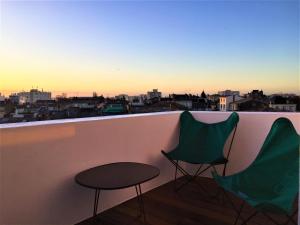 2 sillas y mesa en un balcón con vistas en IKO Bordeaux Appartements, en Burdeos