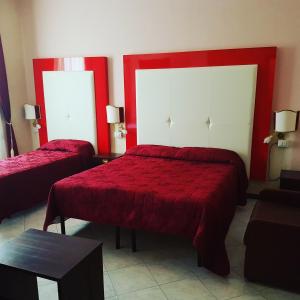 a bedroom with two beds with red covers and a table at Albergo Panorama in Frascati