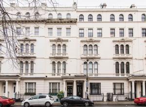 a white building with cars parked in front of it at Kensington Gardens Hotel in London