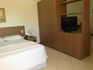 Schlafzimmer mit einem Bett und einem Flachbild-TV in der Unterkunft Crystal Apart Hotel in Macaé