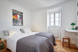 a bedroom with a white bed and white walls at Casas da Comédia in Coimbra