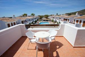 un balcone con tavolo e sedie bianchi e una piscina di Apartamentos Cristina a Cala Millor
