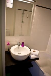 a bathroom with a white sink and a bath tub at The Originals City, Hôtel Anaïade, Saint-Nazaire Pornichet in Saint-Nazaire