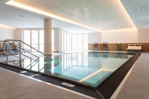 a large swimming pool in a building with a staircase at Das Landerer in Ladis