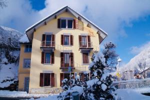 a large yellow building with snow on the ground at Le Chalet Joly in Brides-les-Bains