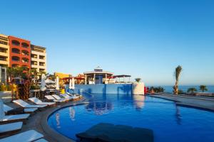 a swimming pool with lounge chairs and the ocean at El Encanto All Inclusive Resort in Cabo San Lucas