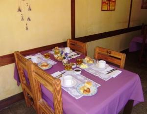 una mesa púrpura con platos de comida. en Hostería Las Gemelas en Capilla del Monte