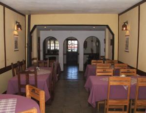 comedor con mesas púrpuras y sillas de madera en Hostería Las Gemelas en Capilla del Monte