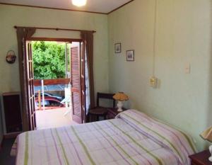 een slaapkamer met een bed en een deur naar een patio bij Hostería Las Gemelas in Capilla del Monte