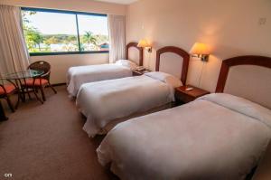 Habitación de hotel con 4 camas, mesa y ventana en Arapey Thermal All Inclusive Resort & Spa en Termas del Arapey