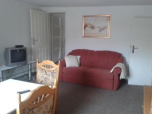 ein Wohnzimmer mit einem roten Sofa und einem TV in der Unterkunft VierZeitHof - Hofcafé EisZeit in Bebertal Zwei
