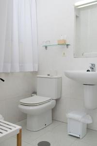 a white bathroom with a toilet and a sink at Hotel Brisa in A Coruña