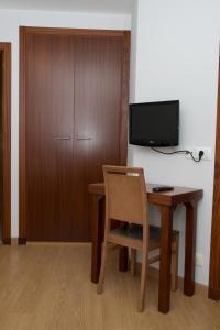 a desk with a chair and a television on a wall at Hotel Brisa in A Coruña