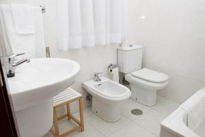 a white bathroom with a toilet and a sink at Hotel Brisa in A Coruña