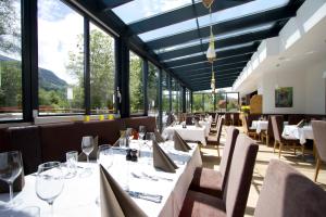 een restaurant met witte tafels, stoelen en ramen bij Hotel Zirngast in Schladming