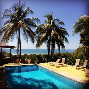 una piscina con palmeras y el océano en Hotel Buenos Aires en Santa Teresa