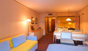 a living room with a yellow couch and a kitchen at Hotel Residence Universo in Pr&eacute;-Saint-Didier