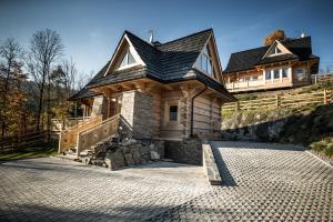 a house with a black roof on top of a hill at Osada domków TATRA-DREAM in Zakopane