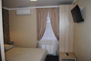 a bedroom with a bed and a window with a television at Gostinitsa DmitrovGrad in Dmitrov