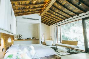 a bedroom with a bed and a bench and a window at July Bamboo Hostel in Deqing