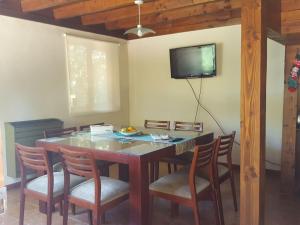 uma mesa de jantar com cadeiras e uma televisão na parede em Cabaña Modern Family em Villa La Angostura