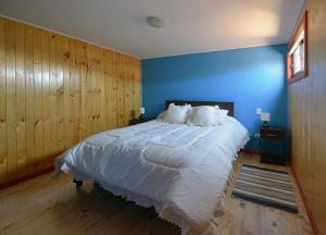 a bedroom with a large bed with a blue wall at Cabaña en barrio Palafitos de Castro in Castro